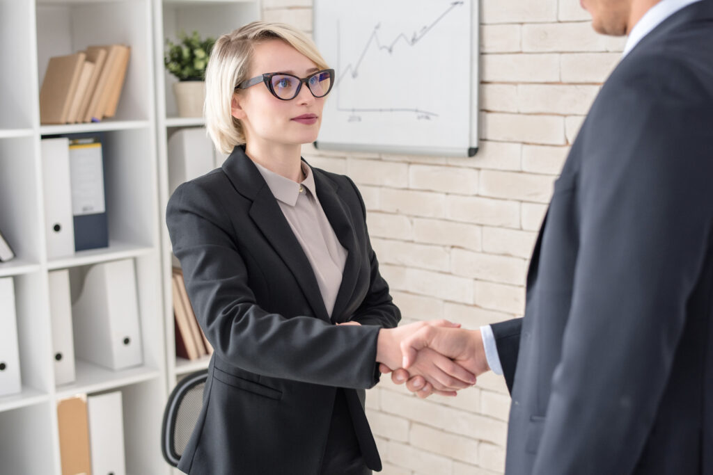 Portrait of successful blonde businesswoman shaking hands with partner after finalizing business deal